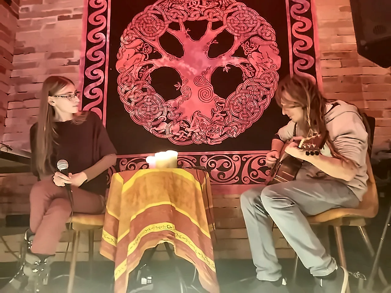 An acoustic duo in front of a Celtic tapestry